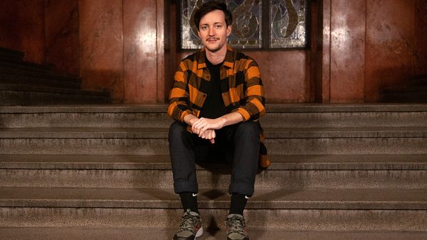 Americký filmař a umělec Rhys Ernst v Praze, sedící na schodech v paláci Lucerna