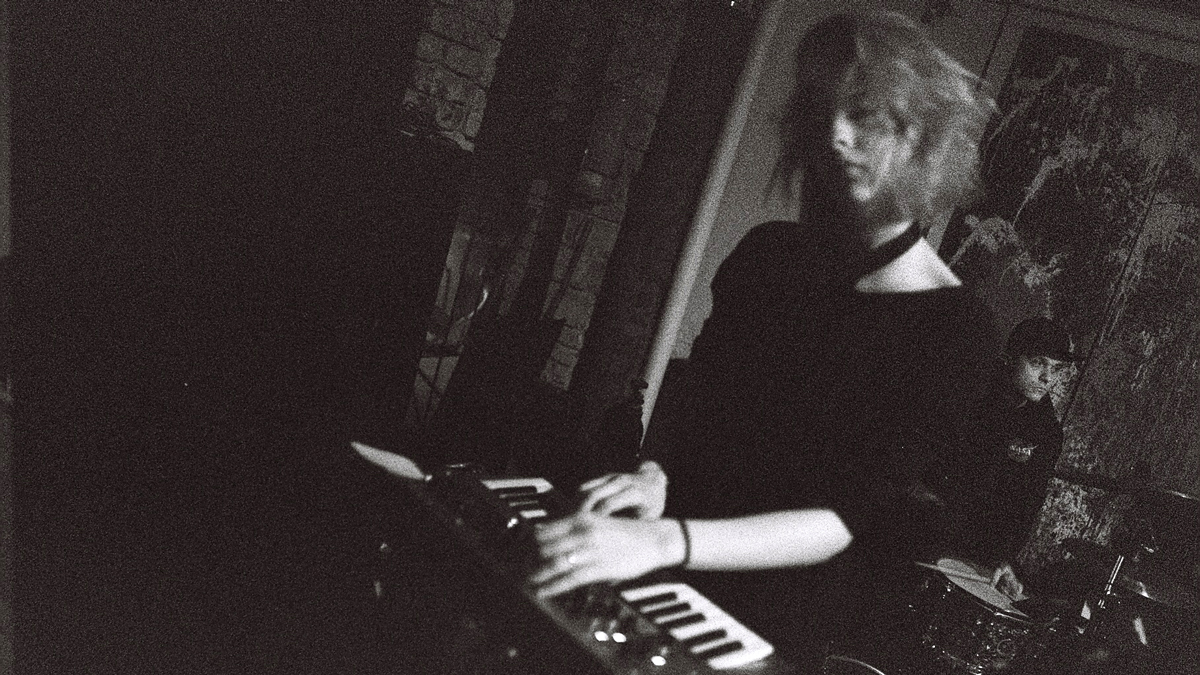 Černobélé foto, klávesistka, v pozadí bubeník