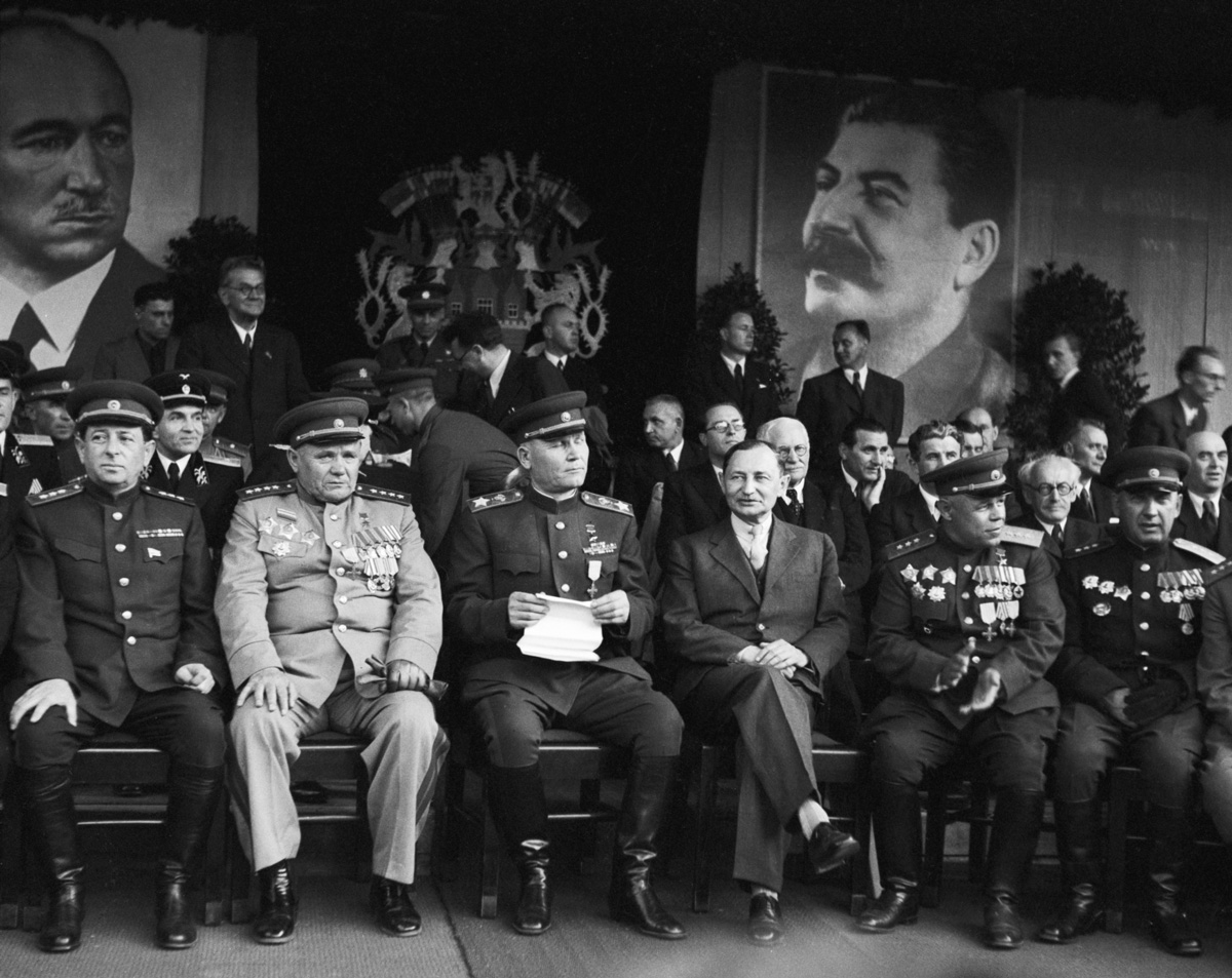 sedící vojevůdci Sovětské armády v uniformách, v pozadí portrét Beneše a Stalina