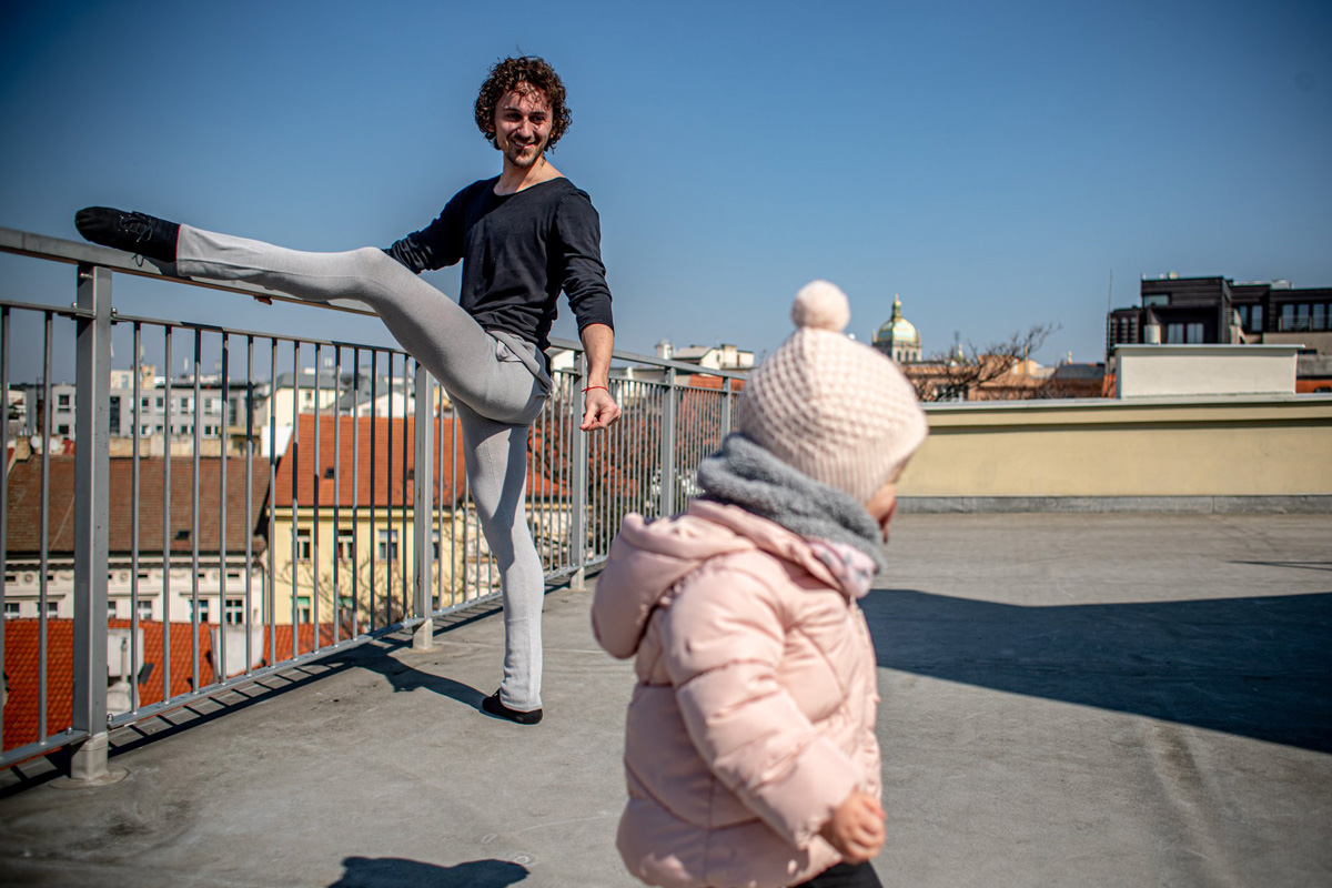 tanečník cvičí na terase, v popředí dítě