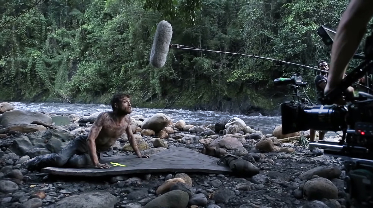 natáčení, muž špinavý od bláta leží vedle kamenité řeky