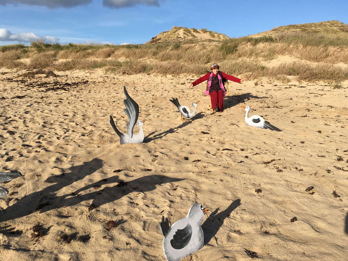 Agnes Vardová sedí na pláži mezi plastikami ptáků