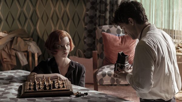 muž fotící ženu u šachovnice
