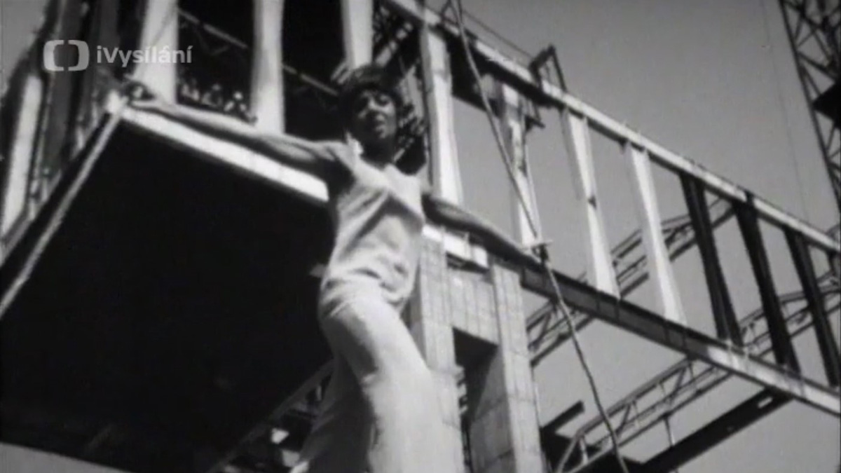 zpěvačka opřená o lana, v pozadí staveniště
