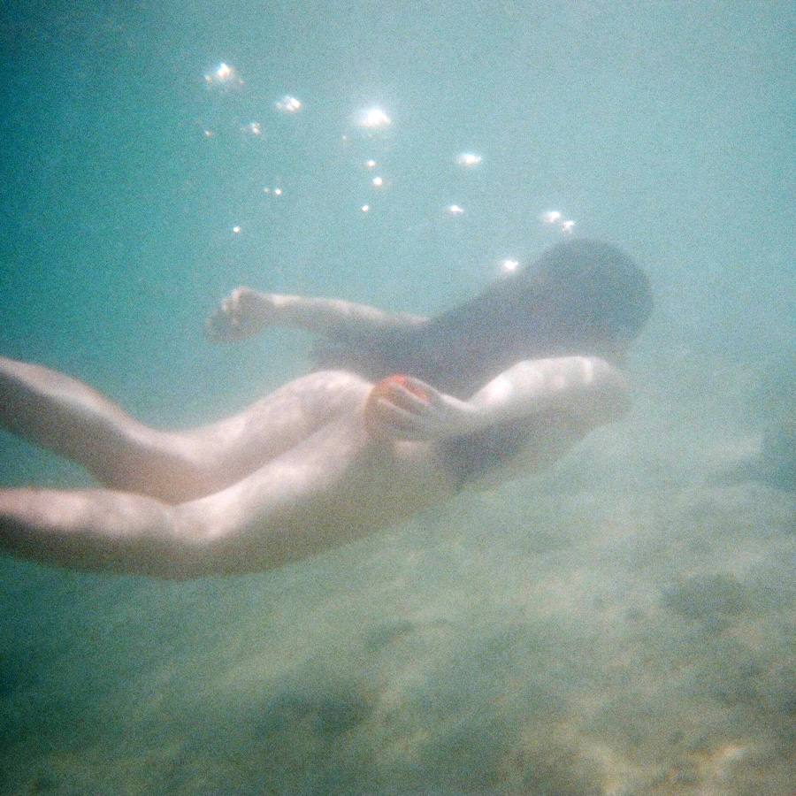 snímek pod vodou, plavající žena držící jablko