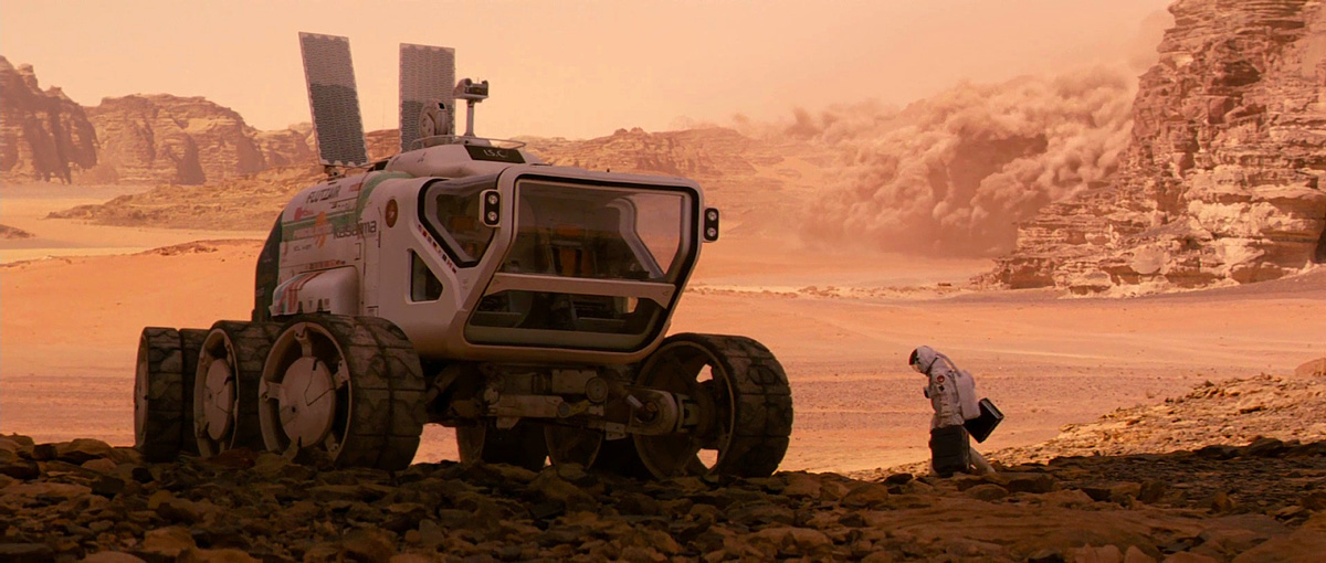 vesmírné vozítko na Marsu a kosmonaut kráčející k němu