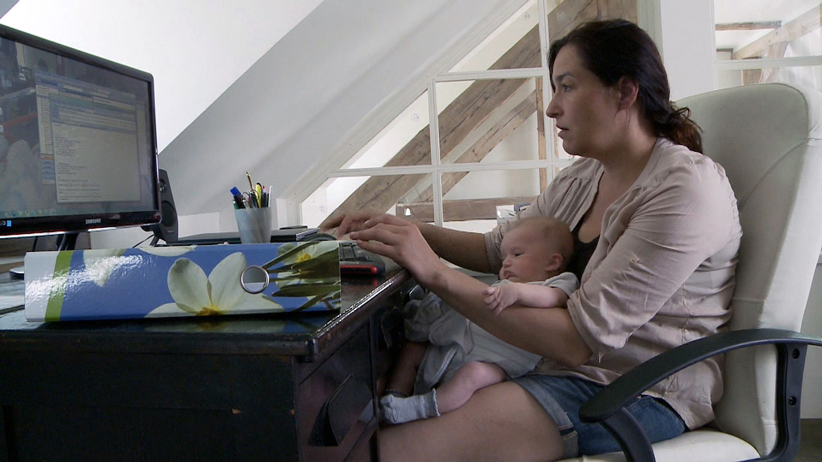 Karolína pracuje na počítači s miminkem na klíně