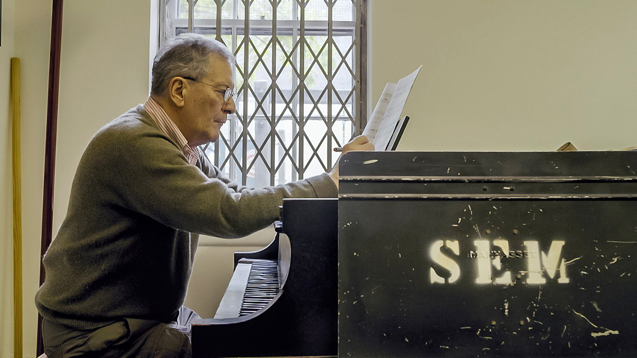 Petr Kotík sedící u&nbsp;klavíru studuje partituru
