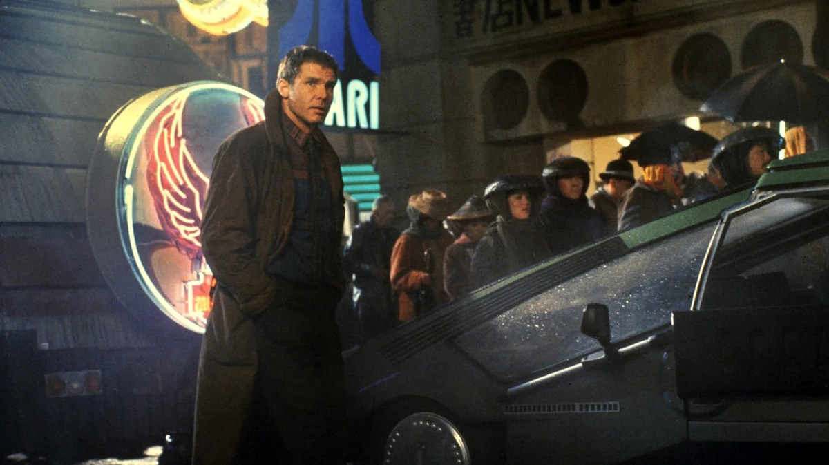 muž v kabátě vedle futuristického auta