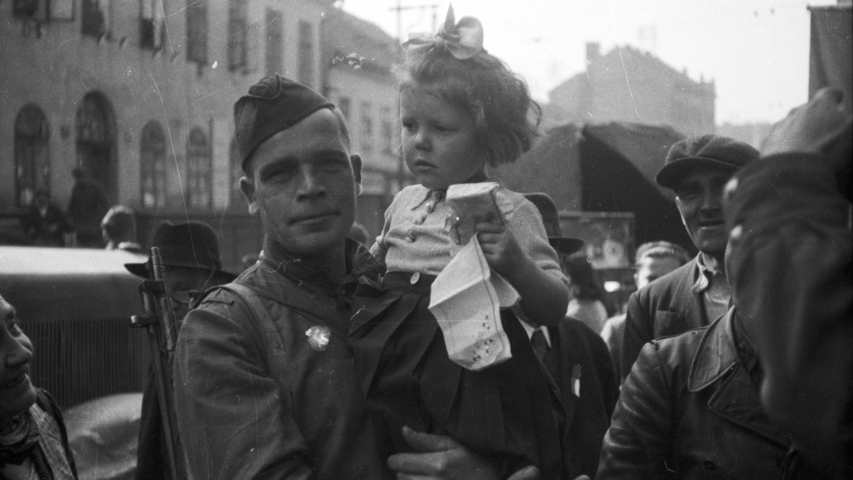 voják s holčičkou v náručí, davy lidí v ulici