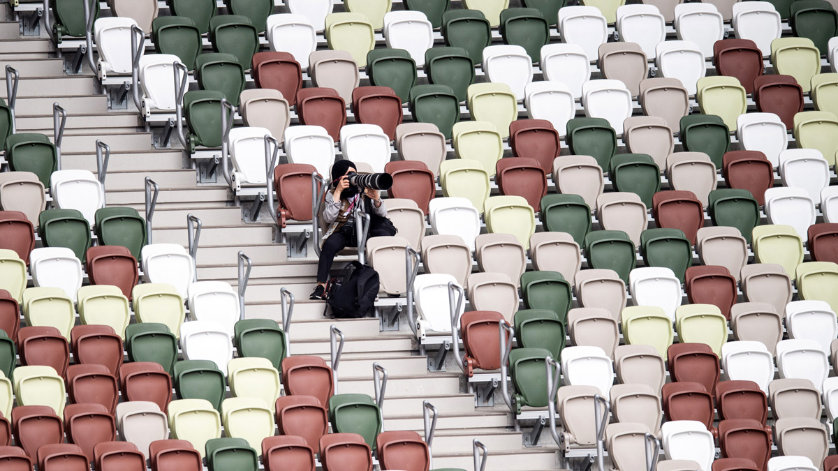 osamělý fotograf v hledišti stadionu