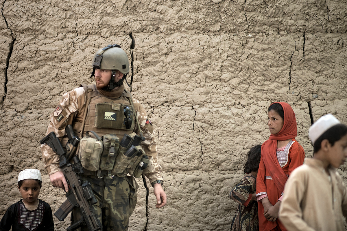 Místní afghánské děti sledují českého vojáka na hlídce ve vesnici poblíž letiště Bagram v Parwanu